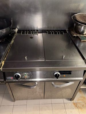 une plaque de cuisson en acier inoxydable dans une cuisine professionnelle, avec des casseroles et des poêles posées dessus