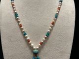 a white mannequin necklace with a turquoise pendant and pearls