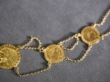 a close up of a necklace with gold coins on it