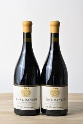 two bottles of red wine sitting on top of a wooden table