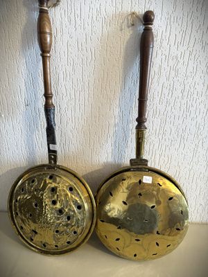 une paire de casseroles et poêles anciennes en laiton accrochées au mur