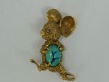 an image of a gold mouse with a turquoise stone in its mouth