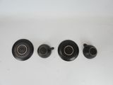 three black and gold teapots and saucers on a white surface
