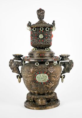 a silver vase with a clock on top of it