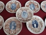several plates with portraits of people on them on a red table