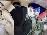 a pile of clothes that is sitting on a bed
