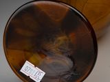 a brown vase with a label on it sitting on a table
