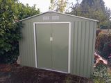 a green shed with a white door in the yard