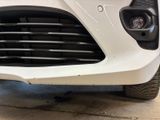 the front end of a white car with a black grille