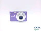 purple digital camera sitting on a white surface with a white background