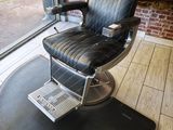 une photo d'un fauteuil de coiffeur devant un mur de briques