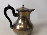 a silver tea pot with a black handle on a table