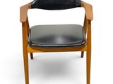 a wooden chair with black leather seat on a white background