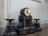 a clock sitting on top of a table next to two stools
