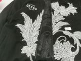 black bomber jacket with white embroidery on the back of it