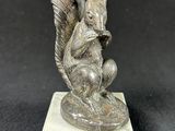 statue of a squirrel on a marble base on a black background