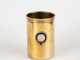 gold cup with a blue emblem on it sitting on a white surface