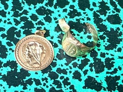 a gold coin and a silver ring on a green surface