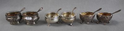 five silver cups and spoons are lined up on a table