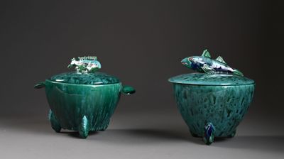 deux vases verts surmontés de poissons, posés sur une table