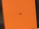 a close up of an orange box on a bed with a white sheet