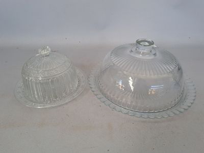 two clear glass dishes with lids on a white surface