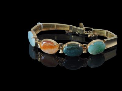 un gros plan d'un bracelet orné de pierres sur un fond noir