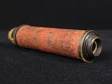 an old red and gold metal tube on a black background