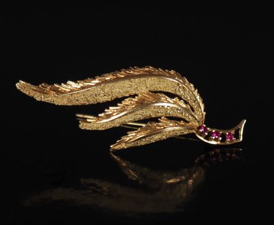 une broche en feuille d'or ornée de pierres roses sur un fond noir