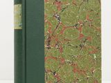 an old book with a green cover sitting on a white surface