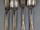 four silver spoons and two forks are lined up on a gray surface