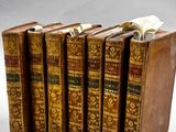 six vieux livres sont alignés sur une surface blanche