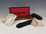 trois paires de gants en cuir dans un étui posé sur une surface blanche