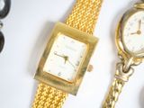 a gold watch and a gold bracelet on a white surface