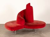 an image of a red chair with a curved seat on a concrete floor
