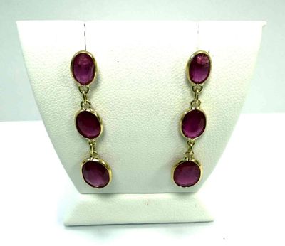 une paire de boucles d'oreilles dorées ornées de pierres violettes, exposée