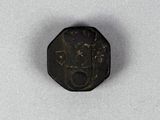 an old coin with a face on it sitting on a white surface