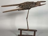 sculpture représentant un oiseau posé sur un banc, réalisée à partir de morceaux de bois