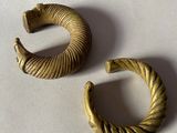 une paire de boucles d'oreilles créoles dorées posées sur un fond blanc