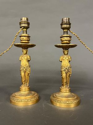 paire de bougeoirs anciens en laiton ornés de figurines sur leurs socles