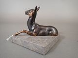statue of a deer laying down on a marble base