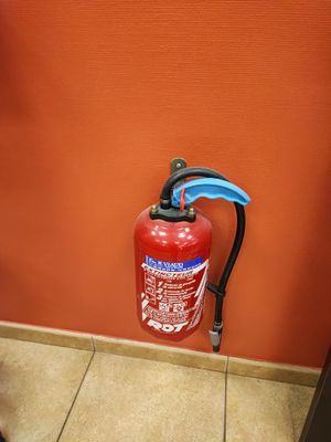 a fire extinguisor on the floor next to a toilet