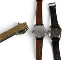 three different watches sitting next to each other on a white surface