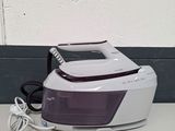 a white and purple steam iron sitting on a counter