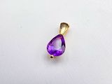 un gros plan d'un pendentif violet en forme de larme posé sur une surface blanche