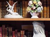une bibliothèque sur laquelle sont posés de nombreux livres et un vase contenant des fleurs