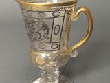 a glass cup with a gold handle on a gray surface