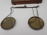 two antique brass weights on a wooden stand on a white surface