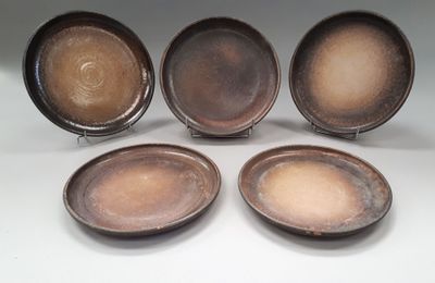 four brown plates sitting on top of each other on a white surface
