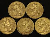 four gold sovereigns of different sizes and shapes on a black background